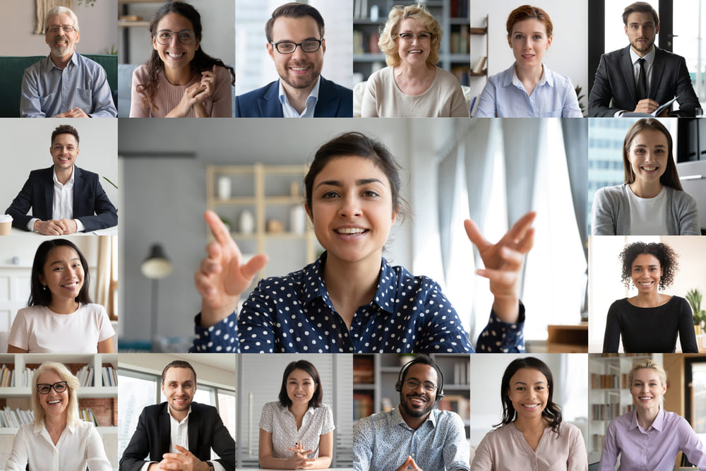 Smiling diverse team of professionals participating in an online video conference, showing multiple people on screen communicating and collaborating remotely